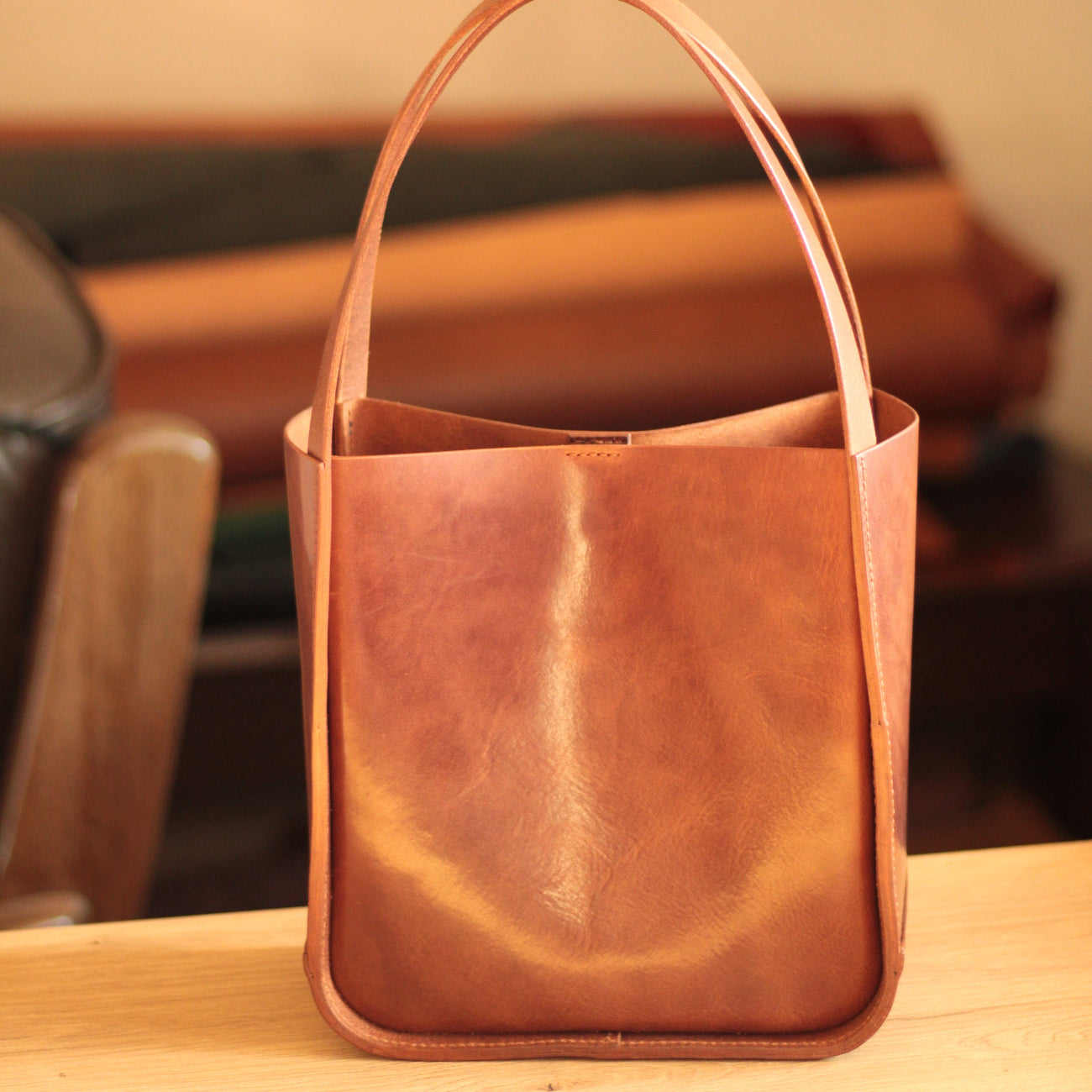 Torba tote w stylu boho, rzucona na drewnianą ławkę w parku.

